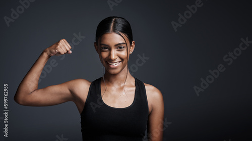 Portrait, smile and woman flexing bicep in studio isolated on a black background mockup space. Strong, happy and female athlete with muscle, arm strength and bodybuilder ready for fitness workout.