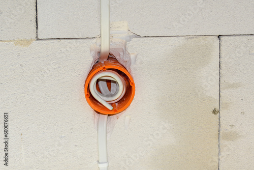 Przewód elektryczny ukryty w ścianie za pomocą pomarańczowej plastikowej puszki elektrycznej. 