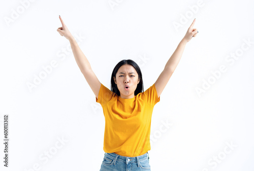 Young excited Asian woman in yellow t-shirt raised her hands up feels a sense of victory, won the lottery, got good news, happy for success standing isolated on white background. Winner gesture