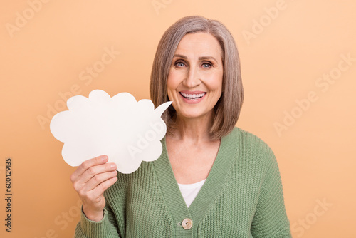 Portrait photo of senior beautiful woman hold bubble cloud speech empty space excited say information isolated on beige color background