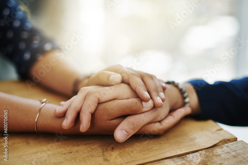 Holding hands, support and closeup with trust, solidarity and community on a home table. Therapy, diversity and gratitude of friends together with hope, respect and love for grief empathy and forgive