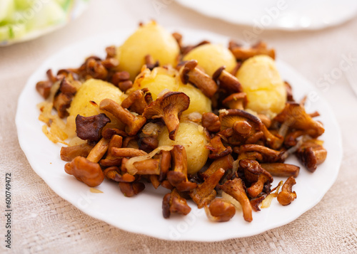 appetizing fried chanterelle mushrooms with new potatoes on white plate