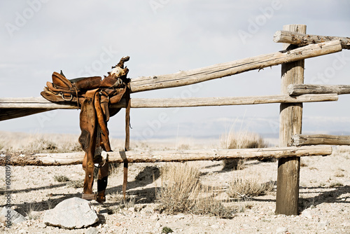 ranch scene - saddle on rural fence, vintage worn saddle in the dry and barren countryside