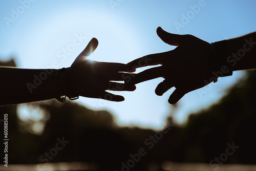 manos rozándose los dedos, a través de una increíble y magnifica puesta de sol, dando un adiós definitivo entre una pareja. 