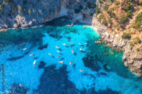 Top drone view of boats and yacths in transparent azure water at sunset. Aerial view of boats in clear blue sea in Sardinia, Italy. Beautiful tropical seascape. Nature. Rocky sea coast. Sea lagoon