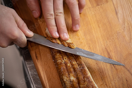 Chef slicing unagi eel with knife for japanese sushi rolls cooking