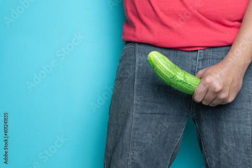 man hand holding cucumber. concept of man erection or hard penis isolated blue background