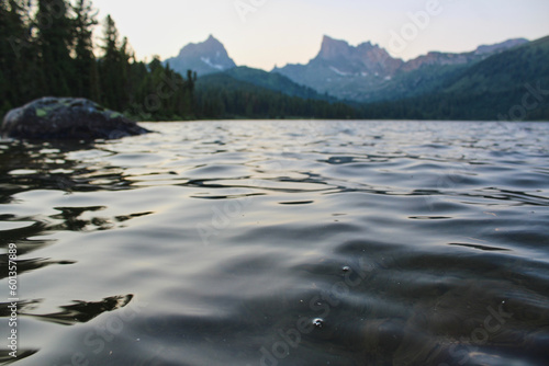 Rippling water in mountain lake Svetloye. Twilight on Shore of pond in Ergaki. Summer landscape