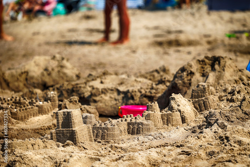 Piaszczysta plaża z zamkami na piasku i zabawkami. 