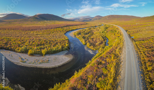 Aerial view from a drone over tundra landscape with hills, a meandering river and an unpaved road in the vicinity of Nome, western Alaska 