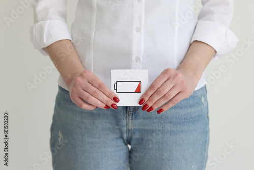 Woman in jeans and shirt shows discharged battery cell image
