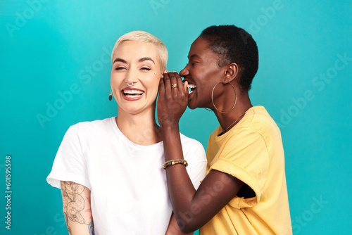 Whisper, secret and girl friends portrait with privacy, laugh and gossip in a studio. Blue background, women and smile of a female person with diversity and funny news telling a story and listening