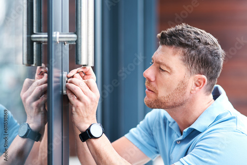 Door, locksmith and man at a house for home renovation, repair and diy lock, change or installation. Safety, maintenance and male handyman person checking keyhole for security or entrance inspection