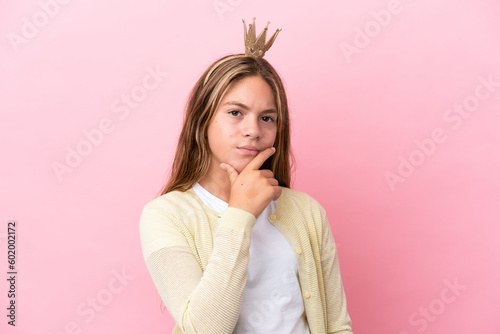 Little princess with crown isolated on pink background thinking