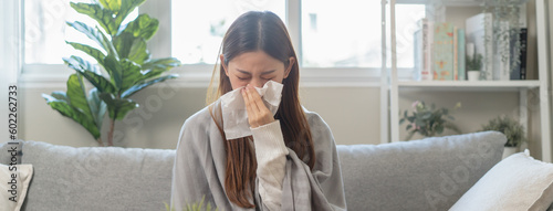 Seasonal sick concept. the young woman has a common cold and sneezing on the sofa.