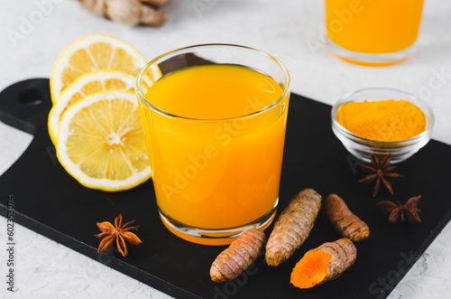 Turmeric Tea, Healthy Beverage with Turmeric Root and Spices, Jamu Juice, Immunity Booster Drink on Grey Background