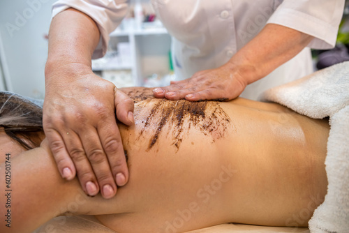 therapist specialist makes a therapeutic massage on the back of a female client in a spa salon