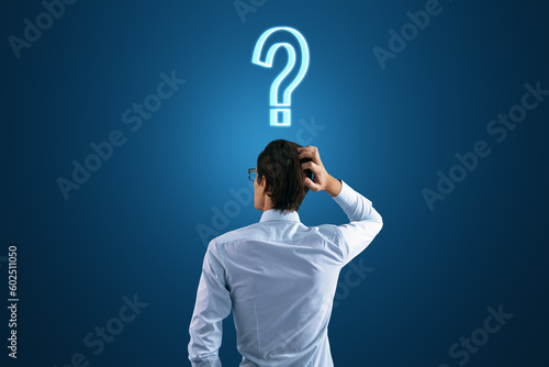 Back view to a thoughtful businessman and a question mark on his head on a dark blue background, search for a solution and doubt concept