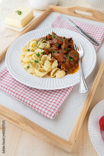 Poultry ragout with buttered shell pasta on a plate