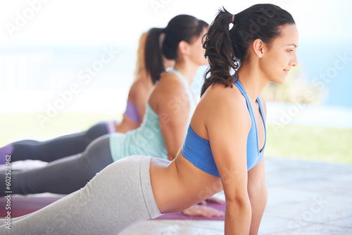 Woman, yoga and instructor in zen workout for fitness, exercise or training together in healthy wellness. Female yogi coach, mentor or personal trainer with group in svanasana pose on mat outdoors