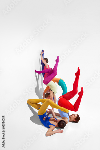 Young girls, ballet dancer in bright tights and bodysuits dancing against grey studio background. Self-expression. Concept of beauty, creativity, classic dance style, elegance, contemporary art