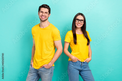 Photo portrait of couple youngsters wear yellow t-shirt denim jeans hands pockets confident good glasses isolated on aquamarine color background
