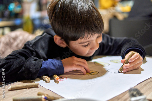 Latino little boy in a bar entertaining drawing and painting with a paper and colored pencils. entertainment without screens, cell phone. didactic games.. Selective focus