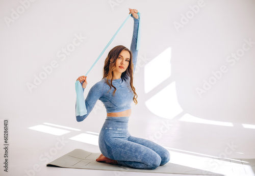 Woman during her fitness workout at studio with rubber resistance band on yoga mat