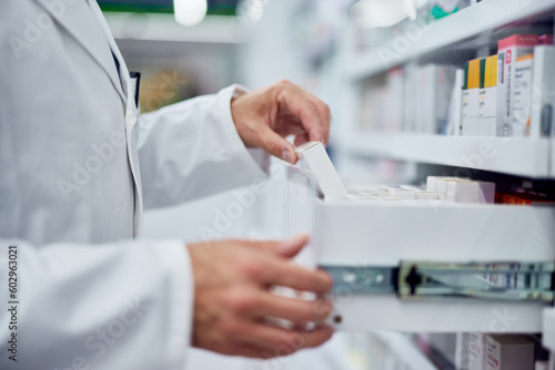 Side view of an pharmacist, taking a box of medicine, dressed in a white uniform.