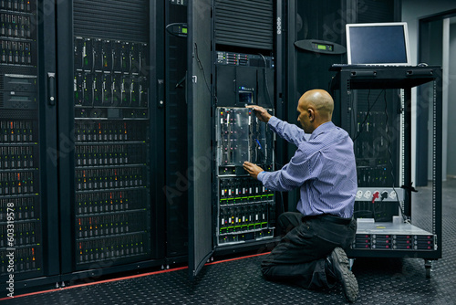 Database, software and a man engineer in a server room for cybersecurity maintenance on storage hardware. Computer network or mainframe with a technician working on information technology equipment