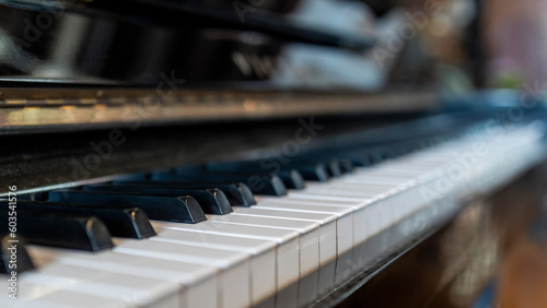 Piano keyboard in inclination angle with selective focus. Warm color toned image with orange light effect.Blur background with space.Black and white grand piano.Nobody or people.