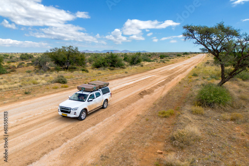 Drone image of offroad vehicle driving on dirt road in African bush