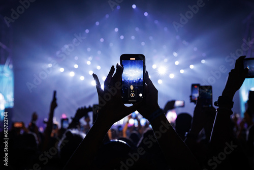 People at concert shooting video or photo using mobile phones.