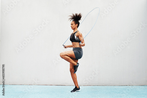 Jump, skipping rope and training with woman in stadium for sports, workout practice and cardio. Performance, health and body with female athlete jumping on track for strong, mockup space and exercise