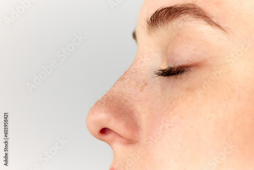 Young woman, girl demonstrating nose after, before surgery over white studio background. Side view. Rhinoplasty