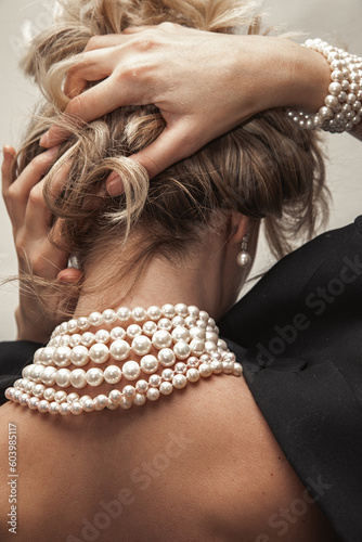 Beautiful young blondy woman with a lot of jewelry around her neck. Lots of pearl necklaces and bracelets.