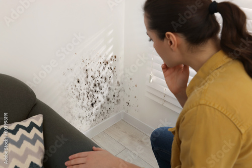 Woman looking at affected with mold walls in room