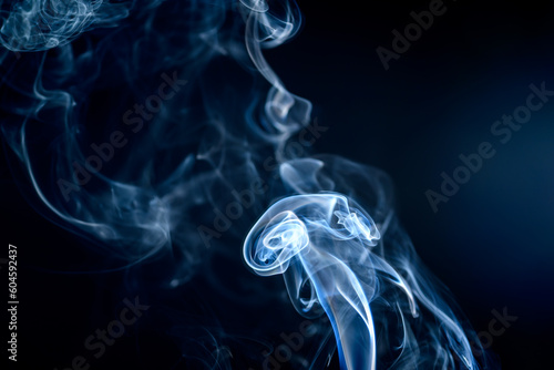 Falujący dym z kadzidełka unoszacy się w powietrzu na czarnym tle