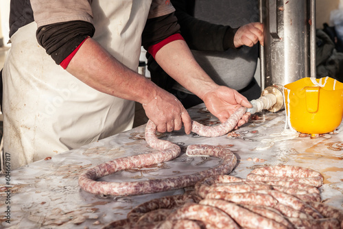 Selective blur on a sausage machine with hands of male people, butchers, making sausages in the countryside of Serbia. Sausage, or Kobasica, is a traditional food from Balkans.