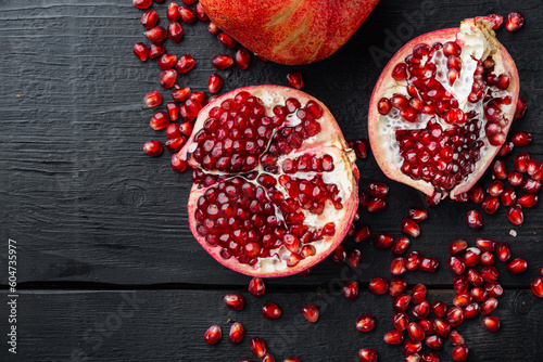 Ripe pomegranate with fresh juicy seeds, on black wooden table, top view