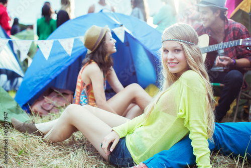 Portrait woman hanging out with friends outside tent at music festival