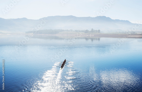 Rowing team rowing scull on lake