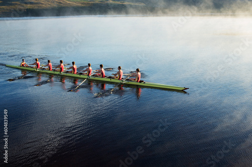 Rowing crew rowing scull on lake