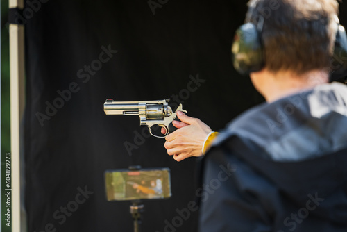 Shooting from a revolver in a shooting range outdoors.