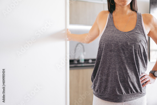 unrecognizable woman in sportswear doing pectoral stretch with arm supported at home. copy space.