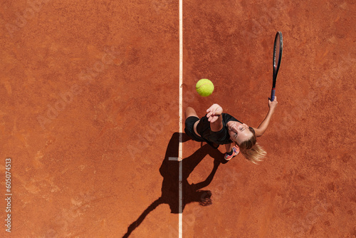 Top view of a professional female tennis player serves the tennis ball on the court with precision and power