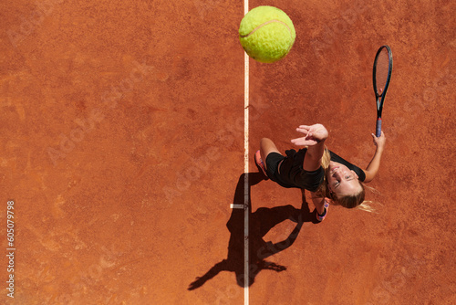 Top view of a professional female tennis player serves the tennis ball on the court with precision and power