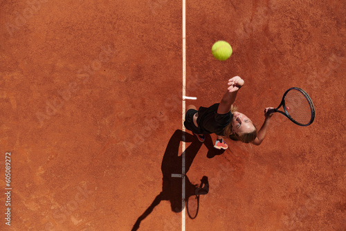 Top view of a professional female tennis player serves the tennis ball on the court with precision and power