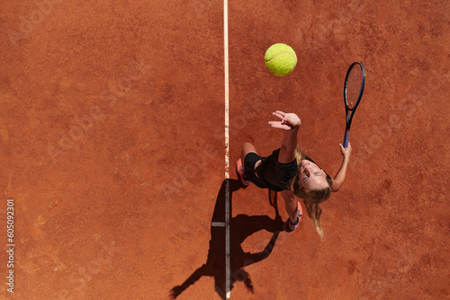 Top view of a professional female tennis player serves the tennis ball on the court with precision and power