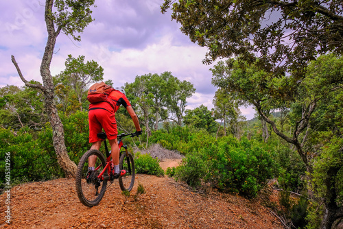 Unrecognisable mountain biker rides a beautiful trail on red earth, Massa Marittima, Tuscany, Italy